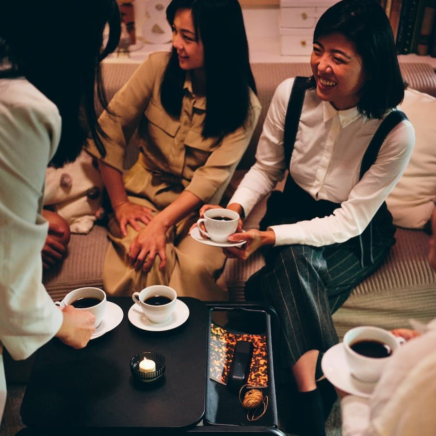 Zwei Frauen sitzen auf einem Sofa und trinken Kaffee.