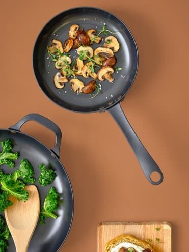 Zwei gusseiserne VARDAGEN Pfannen von oben mit Lebensmitteln gefüllt.