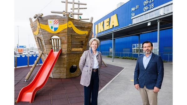 Zwei gut gekleidte Personen stehen bei einem Spielplatz vor einem Ikea Store