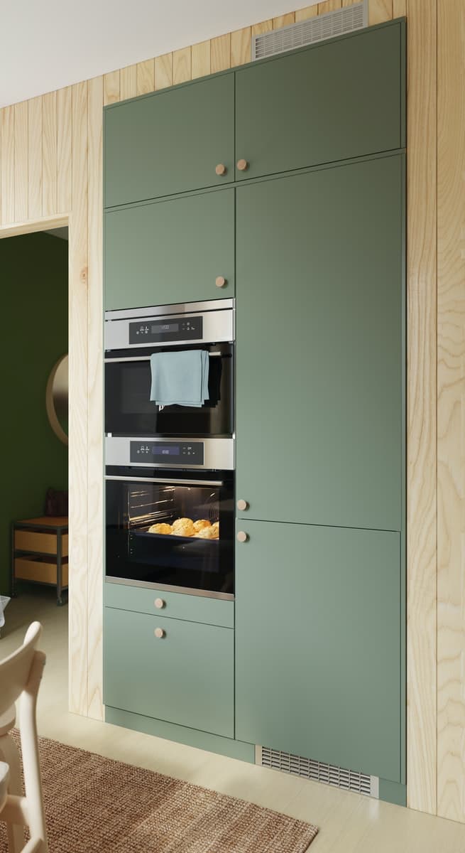 Zwei Hochschränke in der Wand verbaut. Im linken sieht man eine Mikrowelle und einen Backofen. Hinter dem rechten verbirgt sich ein Kühlschrank.