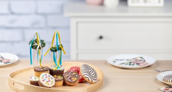 Zwei Midsommerbäumchen dekorieren Muffins, die auf einem Tablett sitzen. 