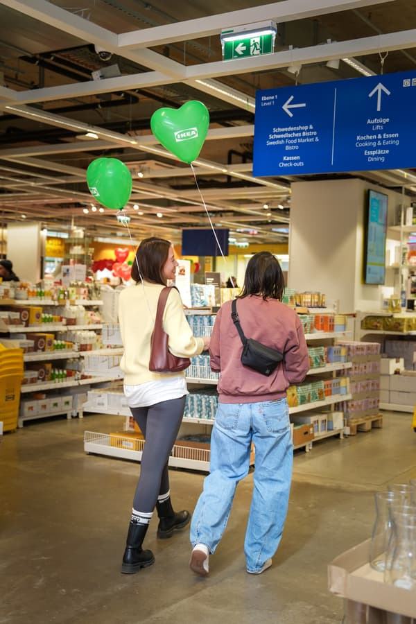 Zwei Personen gehen mit einem grünen Luftballon.