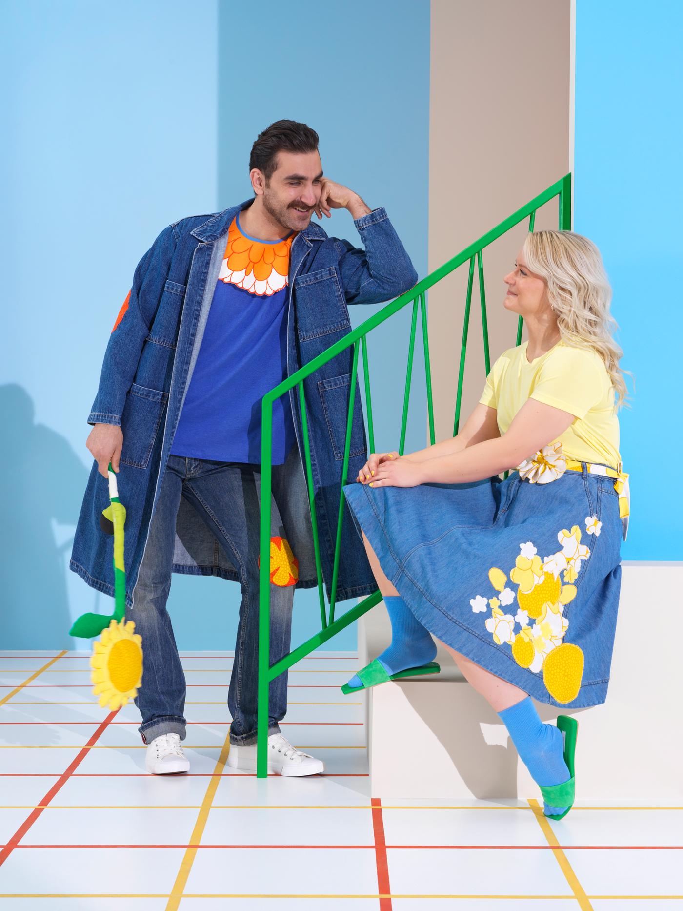 Zwei Personen in Jeanskleidung mit Aufnähern in einem Blumenmuster lächeln einander an. Die Aufnäher sind aus SANDETERNELL Stoffbahn gefertigt.