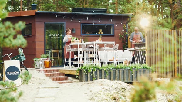 Zwei Personen richten ein Pop-up-Restaurant im Wald ein. Dazu stellen sie auf der Terrasse SEGERÖN Möbel für draußen auf.