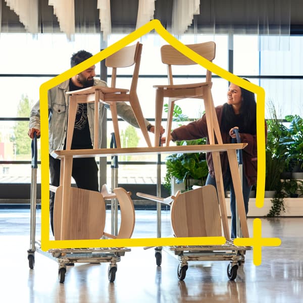 Zwei Personen schieben zwei Einkaufswägen mit Stühlen darauf.