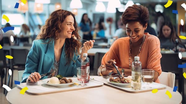 Zwei Personen sitzen in einem IKEA Restaurant, lachen und essen eine Mahlzeit.