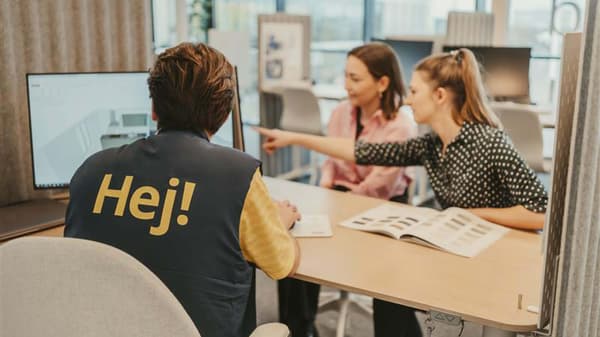 Zwei Personen sitzen mit einem IKEA Mitarbeiter an einem Tisch.