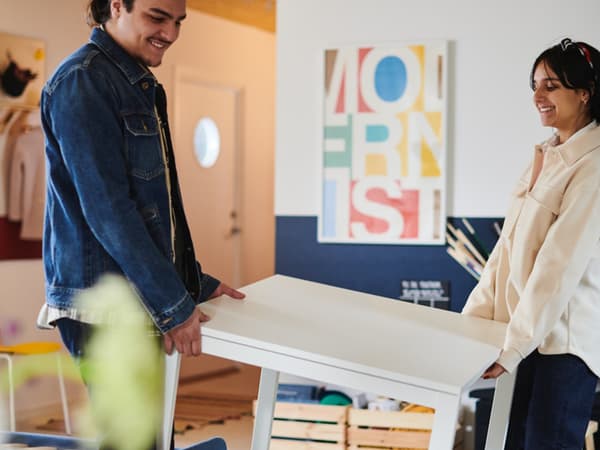 Zwei Personen tragen einen weißen IKEA Tisch.