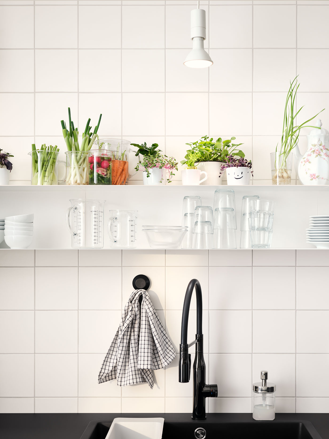 Zwei Regale mit Glasbehältern und Gemüselebensmittelresten hängen über einer schwarzen Arbeitsplatte mit einer schwarzen Mischbatterie.