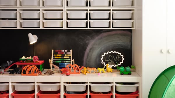 Zwei TROFAST Kombinationen stehen vor einer Wand mit Tafelfarbe. Vier TROFAST Regalrahmen für die Wand mit weissen Boxen sind darüber befestigt.