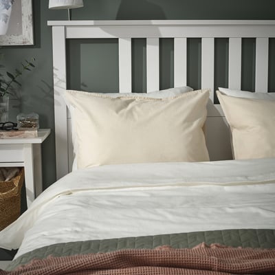 Beige cotton pillowcases & bedding on white headboard with lamp. Alternative: beige cotton pillowcases on bed, duvet, and lamp.