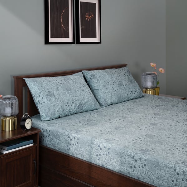 Bed with light blue cotton & lyocell floral bedding, flanked by small nightstands with lamps, and framed art above.