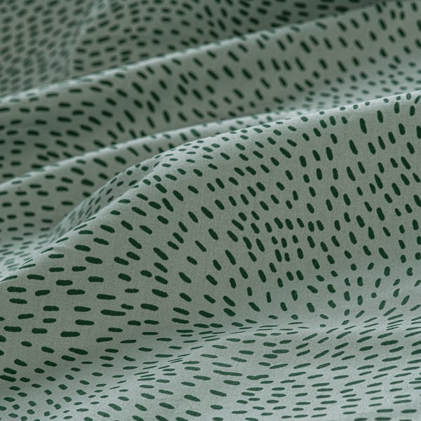 Folded green bedsheet with small white dots; soft, high-quality cotton blend.