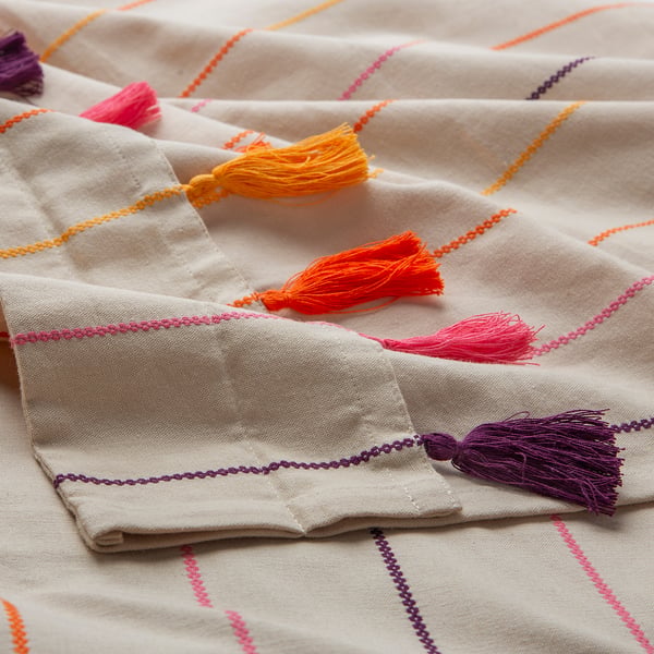 Colourful tassel-trimmed cream curtain, vibrant threads in orange, pink, yellow, purple, adding texture and charm.