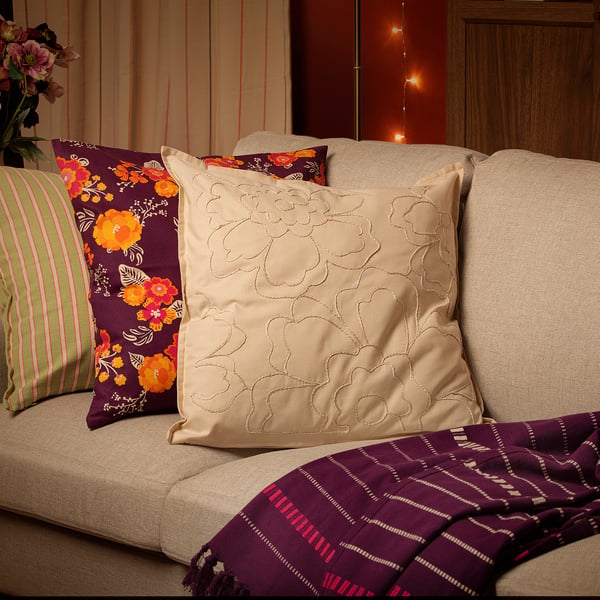 AROMATISK beige cushion, floral embroidery, on large sofa, purple floral & striped pillows.