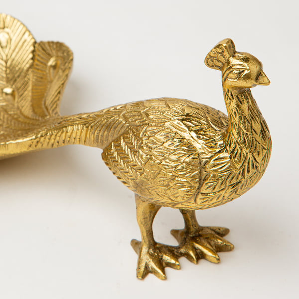 Gold-colored metal peacock figurine with detailed feathers, standing proudly on a table. Ideal for decoration.