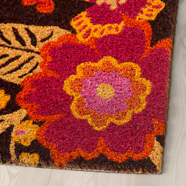 Bright, intricately woven doormat with detailed flower patterns and vibrant colours.