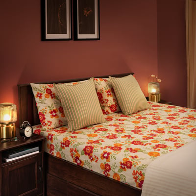 Bedroom with AROMATISK floral bed set in red and orange tones. Matching headboard, lamps, and artwork create cosy, colourful space.