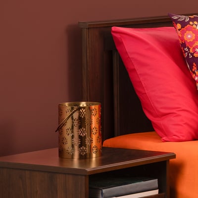 Gold AROMATISK lantern with floral cuts, soft glow, fits cosy setting.