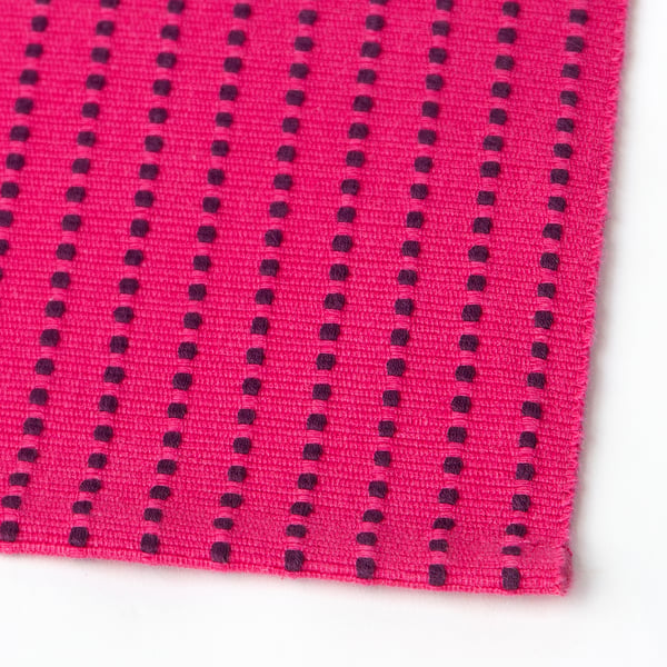 Bright pink textured placemat with dark pink patterned lines, woven from cotton.