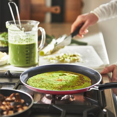 Cooking with green batter in non-stick pan; mushrooms sautéing.