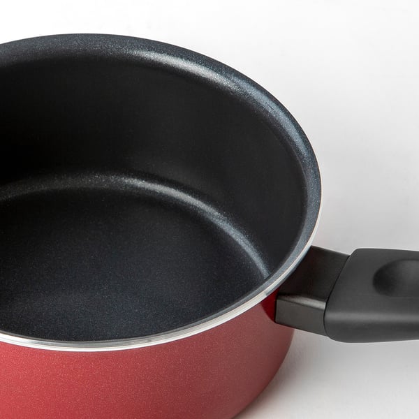 Close-up of a red saucepan with non-stick coating, showing its smooth interior and ergonomic handle.