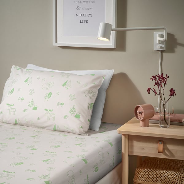 Bedroom with green animal print bed, wall lamp, clock, vase, and inspirational wall art.