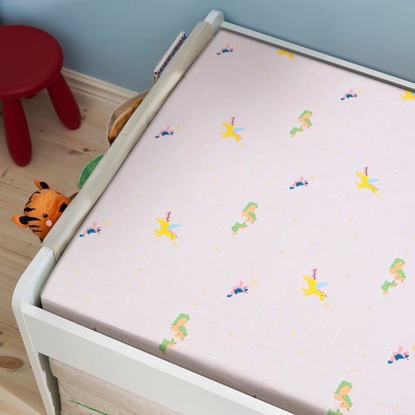 Childs bed with white railing, pink bedsheet featuring flying unicorns. A stuffed tiger toy rests on the bed.