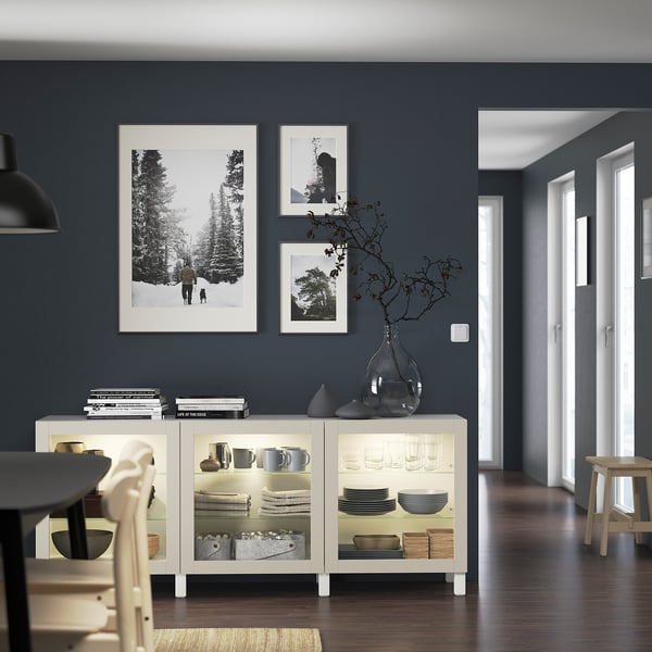 Modern dining room with BESTÅ sideboard, illuminated, displaying plates, cups, and decor.