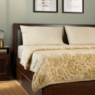 Bed with cream floral BLIXABACKEN blanket, polyester, bedside lamp, books.