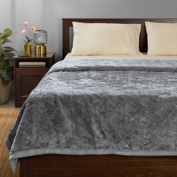 Recycled polyester blanket with geometric pattern on bed.