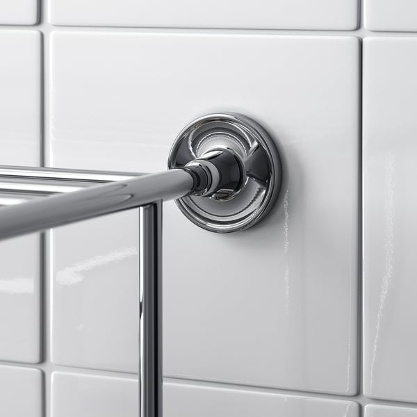 A sleek, chrome-finished towel rail mounted on a white tiled wall. The design is elegant and minimalistic.