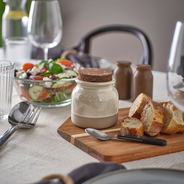 BRUGDHAJ jar with cork lid on wooden table between bread and salad.