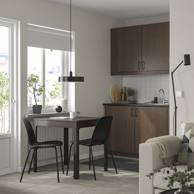 Modern dining set with extendable table and black chairs. Tables wooden top matches dark brown cabinetry; space-saving, sleek design.