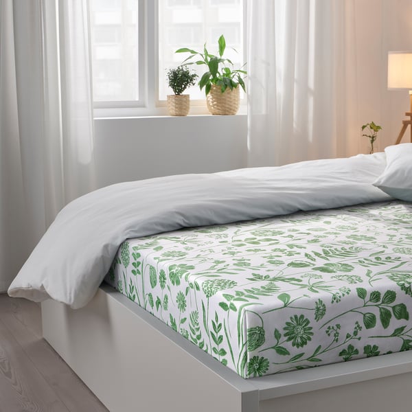A cosy bedroom with a FÄRGARE sheet set featuring green floral prints, providing a fresh and comfy sleep environment.