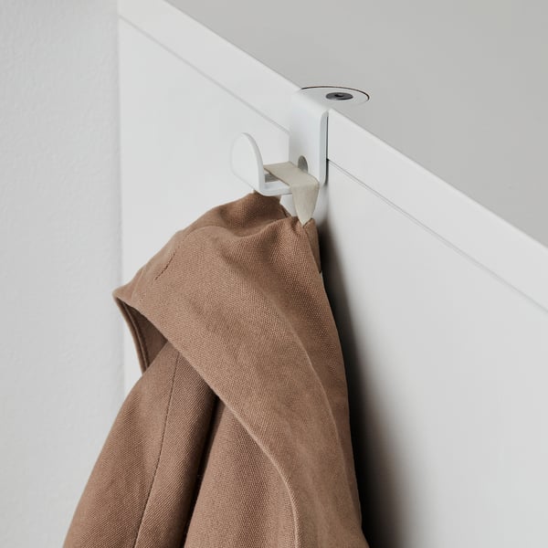 White wall-mounted coat hanger holding brown jacket. Adjustable storage with integrated cable management.