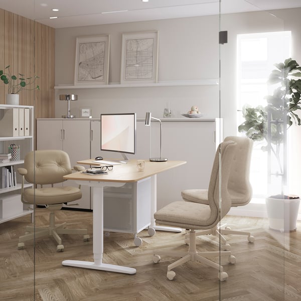 Office workspace with GALANT beige chairs, white desk, and adjustable shelves. Wooden floors, glass partition, natural light, and maps on wall.