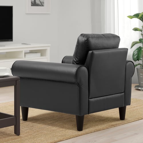 Black leather armchair in living room, with cushions, on rug.