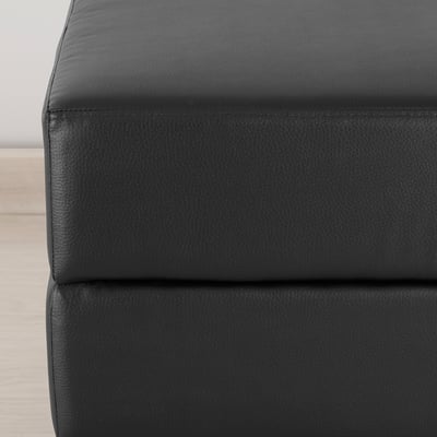 Black square footstool, leather-like, four tapered legs.