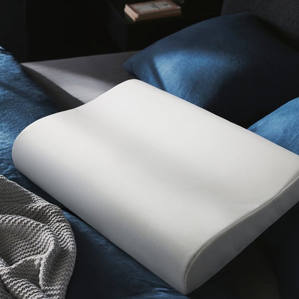 A white GRÖNPIL memory foam pillow on a blue bed, offering comfort for a good nights sleep.