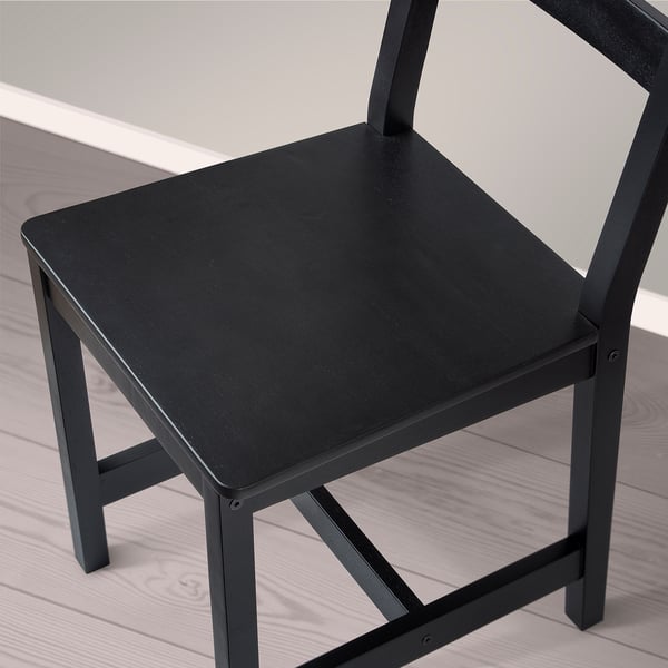 Black wooden chair with rectangular seat and backrest, placed on light wooden floor. Simple, sturdy design.