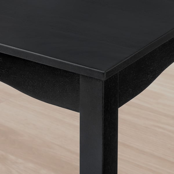 Black wooden table corner with smooth, glossy finish; sturdy, well-crafted.