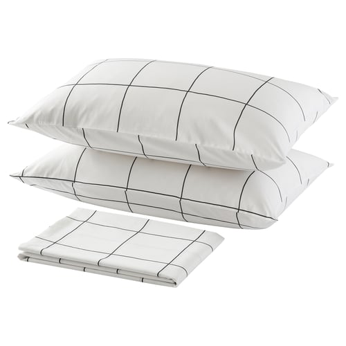 Three white pillows with black grid lines, two stacked and one folded, minimalist bedroom decor.