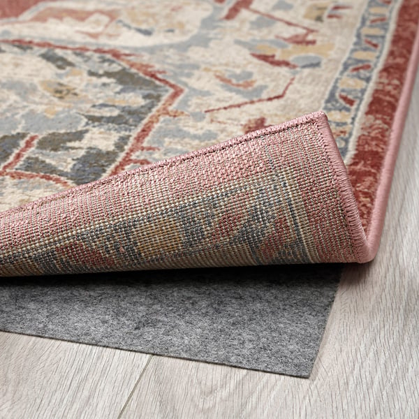 Close-up of a durable, stylish rug with intricate patterns, showing its soft, pastel tones and quality backing on a wooden floor.