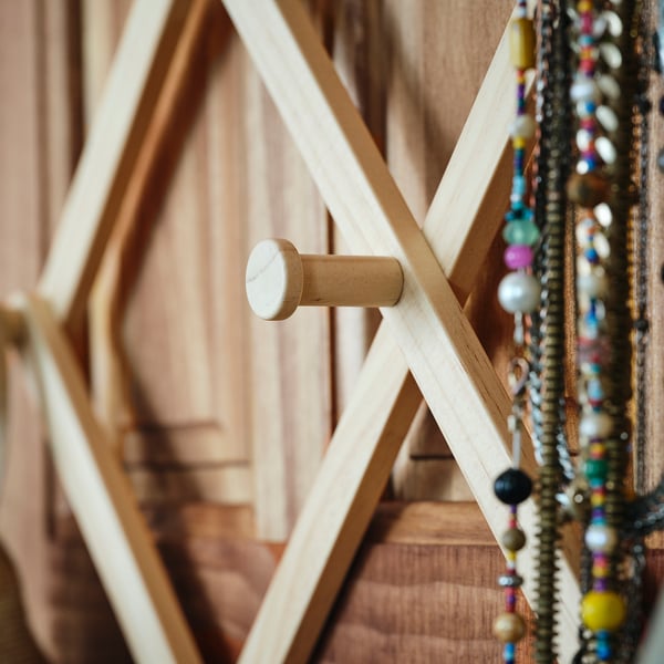 Wooden door hanger with multiple hooks, displaying beaded necklaces. Crafted with natural wood finish and functional design.