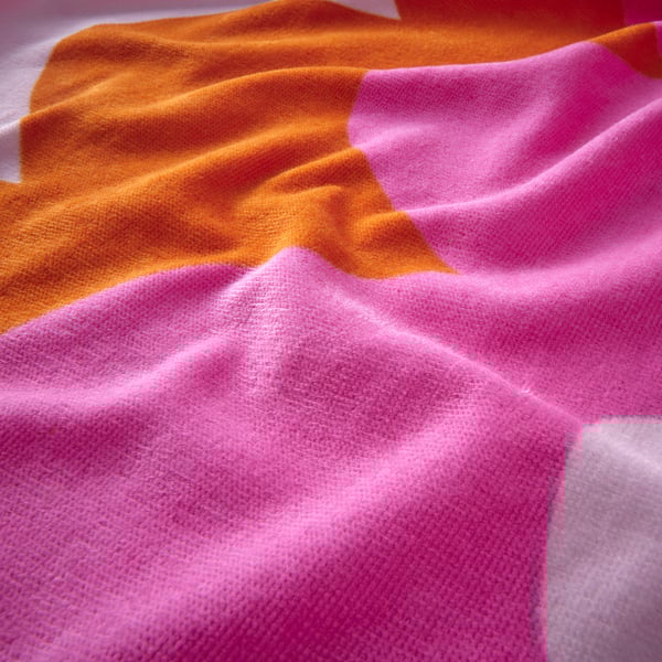 Close-up of soft, vibrant orange and pink cotton towel, showcasing its texture and quality.
