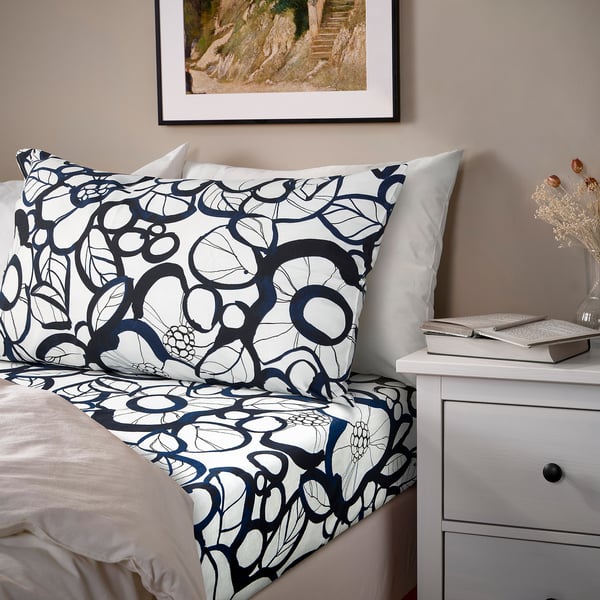 Blue & white floral bedding set on made bed with decorative vase.