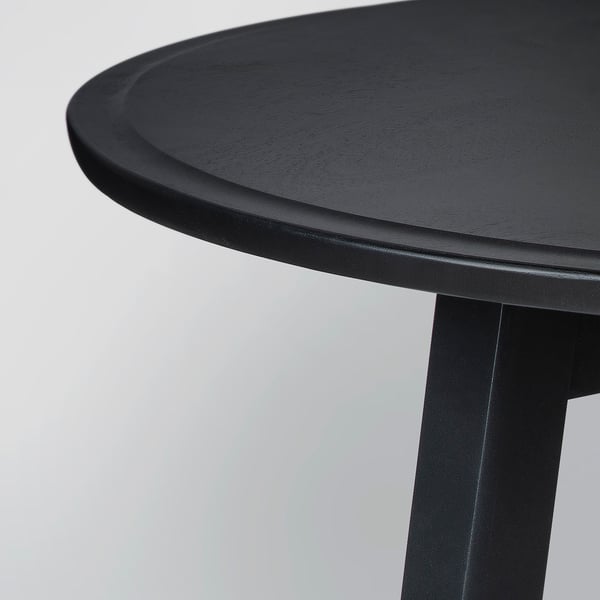 Black round table with smooth, polished surface and sturdy legs.