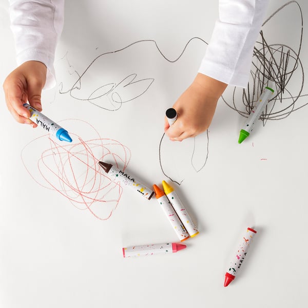 Children drawing with colourful MÅLA crayons on white paper.
