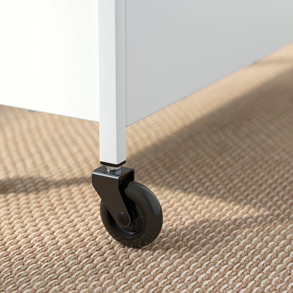 Close-up of a metal trolley wheel on a braided rug. Sturdy and smooth, ensuring easy mobility.